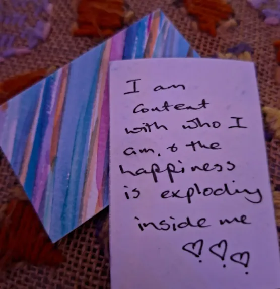 Jane’s handwritten note on a card: “I am content with who I am, & the happiness is exploding inside me”, with three hearts